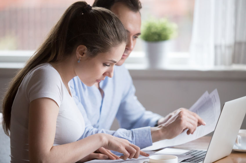 Serious man and woman reading paperwork managing family budget